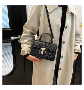 Detailed view of black quilted crossbody bag with golden T-shaped metal twist lock