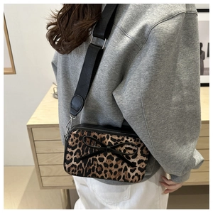 Detailed view of leopard print crossbody bag with black bow on grey casual outfit