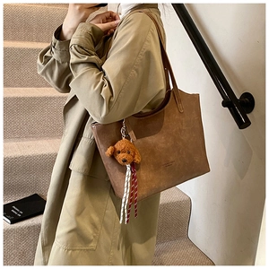 Detail of vintage brown leather bucket bag with cute puppy charm and striped scarf