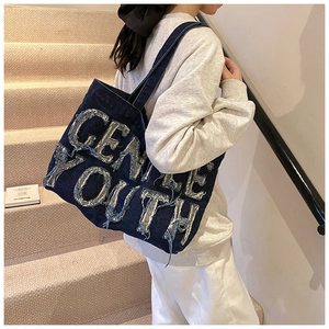 Detail of the blue denim tote bag featuring distressed Gentle Youth lettering