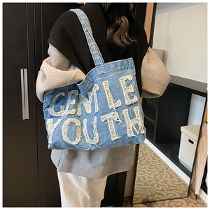 Detail of blue denim tote bag with white Gentle Youth frayed lettering and texture