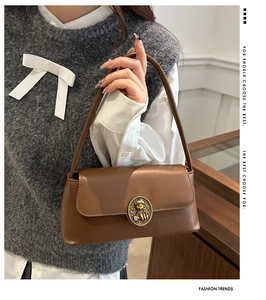 Close-up of brown leather hobo bag featuring vintage round metal embossed buckle and strap