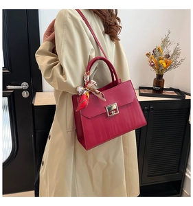 Dettaglio borsa a mano rosa con fibbia dorata e foulard di seta sul manico
