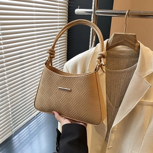 Detail of khaki woven texture handbag with twisted handle and golden metal bar