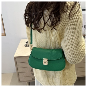 Detail of green litchi grain leather bag with gold buckle on a model's shoulder