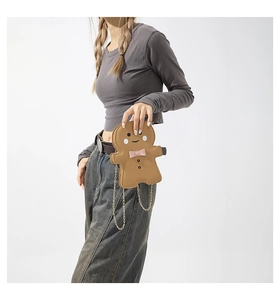 Detail of gingerbread man crossbody bag with pink bow and gold chain strap for women