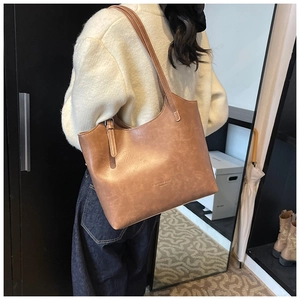 Close-up of brown matte tote bag featuring minimalist exterior stitching and embossed logo