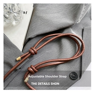 Detail of adjustable brown leather shoulder strap with golden metal end caps for handbag