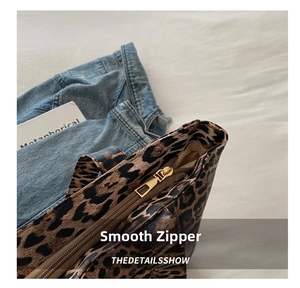 Detail of leopard print tote bag featuring a smooth gold-tone metal zipper and textured fabric