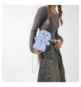 Side view of cute light blue gingerbread man crossbody bag with pink bow and gold chain