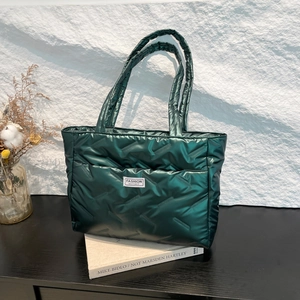 Quilted green down tote bag with a white fashion label on a minimalist setup