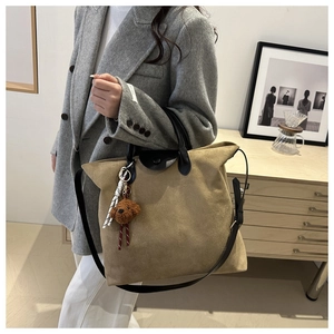 Dettaglio della grande borsa tote in pelle scamosciata con manico e ciondolo orso