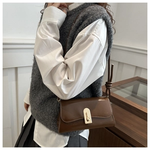 Close-up of retro brown underarm bag with gold bar lock on white shirt and grey vest