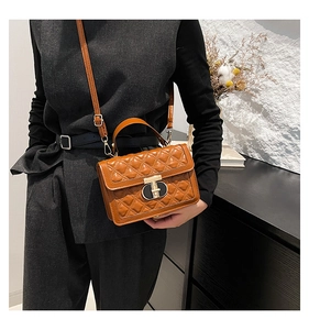 Close-up of caramel leather crossbody bag featuring classic quilted stitching and T-lock