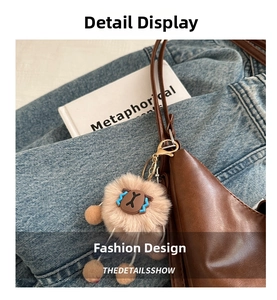 Close-up of a cute plush sheep charm attached to a brown leather tote bag with denim