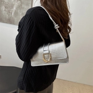 Silver crocodile texture small square bag with gold U-shaped lock on a black outfit