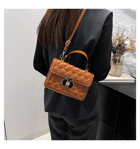 Rear view of a model wearing a brown quilted crossbody bag with golden metal lock