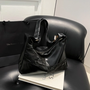 Chic black PU leather tote bag with unique pleated stitching on a black leather sofa