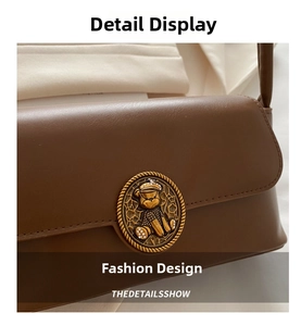 Close-up of brown matte leather handbag with vintage gold bear relief buckle detail