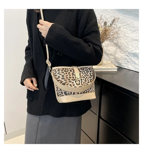 Detail of leopard print bucket bag featuring gold metal clasp and adjustable shoulder strap