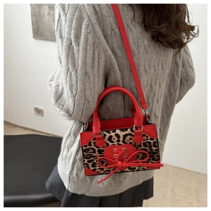 Close-up of leopard print mini bag with red heart patch and bow detail on grey sweater