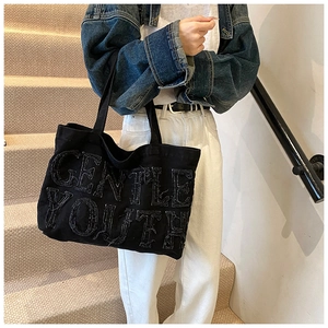 Detail of GENTLE YOUTH embroidery on black canvas tote bag with retro frayed edges