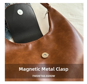 Detail view of the magnetic closure on a brown vintage PU leather crescent shoulder bag