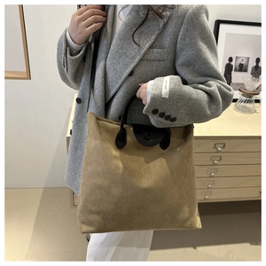 Détail du cabas en daim kaki avec poignée en cuir noir et design rétro minimaliste