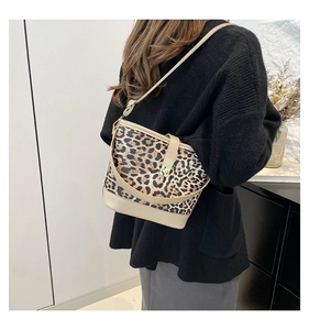 Detail shot of leopard print bucket bag with gold clasp shown on a model