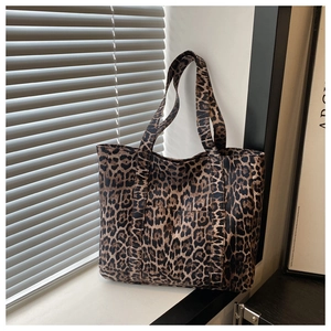 Close-up of leopard print canvas tote bag featuring a front pocket and wide shoulder straps
