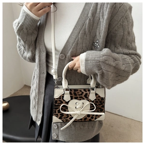 Detail of leopard print handbag featuring cream heart patch and ribbon lace-up design