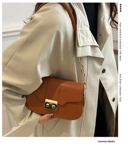 Detail of crocodile pattern leather bag with golden square lock and chain strap