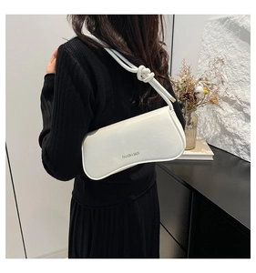 Detail of white matte leather underarm bag featuring knotted shoulder strap and elegant logo