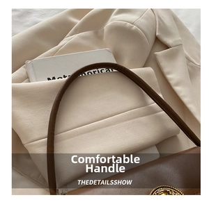 Detail of a brown leather shoulder bag handle with retro metal buckle and sleek texture