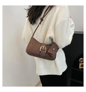 Close-up of vintage brown shoulder bag with metal buckle and small hanging coin pouch