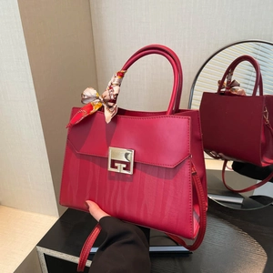 Elegante borsa a mano rossa con chiusura dorata e foulard di seta legato al manico