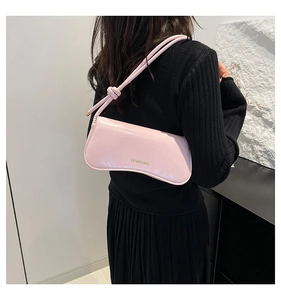 Detalle de bolso rosa con correa anudada e impresión de logo dorado en el frente