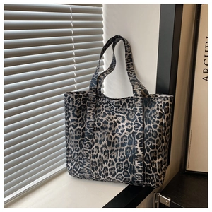 Detailed view of the leopard print canvas texture and straps of the large tote bag