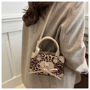 Detail of leopard print handbag featuring a beige heart patch and stylish cross-lacing