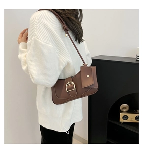 Close-up of brown vintage shoulder bag with gold horseshoe buckle and small pouch