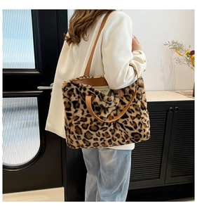 Fashionable leopard print faux fur tote bag with brown leather strap worn by a model