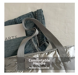 Detail of silver quilted puffer tote bag with durable woven handles and glossy metallic finish