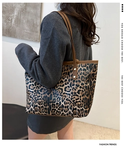 Detailweergave van grote luipaardprint tote bag met bruine lederen riemen en klinknagels