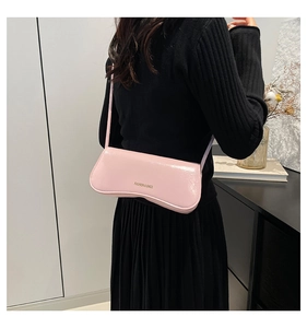 Pink glossy wave-shaped underarm bag shown on model with elegant golden logo detail