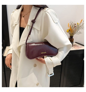 Primer plano del bolso de hombro en charol rojo vino con detalles en dorado