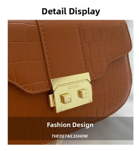 Close-up of brown crocodile pattern leather with square gold metal clasp and stitching