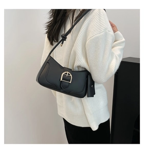 Detail of black crescent shoulder bag with golden horseshoe buckle and mini charm