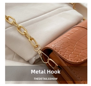 Detailed macro view of the golden metal chain hook on brown crocodile pattern bag