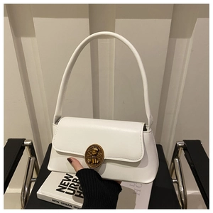 Detail of white baguette bag with vintage gold bear-shaped relief clasp and flap closure