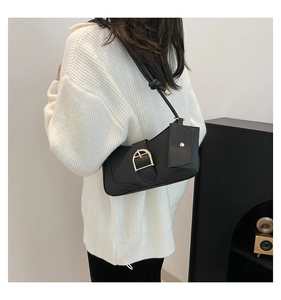 Detail of black crescent shoulder bag with metallic buckle and small detachable pouch